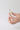 A hand holding a Fleurac fragrance discovery set sample of oil perfume with a silver cap against a plain light gray background.